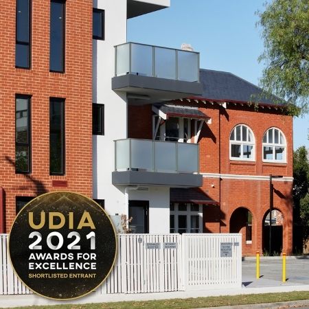 A modern apartment building with glass balconies stands beside a historic red brick building. A circular UDIA 2021 Awards for Excellence Shortlisted Entrant badge is displayed in the bottom left corner.