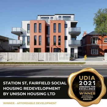 Modern apartment building with large balconies and red brick facade; award badge reads UDIA 2021 Awards for Excellence Winner, Affordable Development Award. Text overlay: Station St, Fairfield Social Housing Redevelopment by Unison Housing Ltd.
